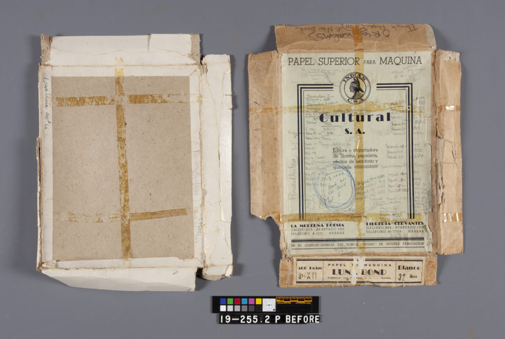 An image of a typewriter paper box lid and tray, both extensively damaged torn, flattened, and wrapped in deteriorating tape, with a typed label that reads PAPEL SUPERIOR PARA MAQUINA / CULTURAL S.A." On the lid, Hemingway's extensive handwritten notations in pencil indicate dates ranging from December to the following April of an undated year, alongside daily word counts.