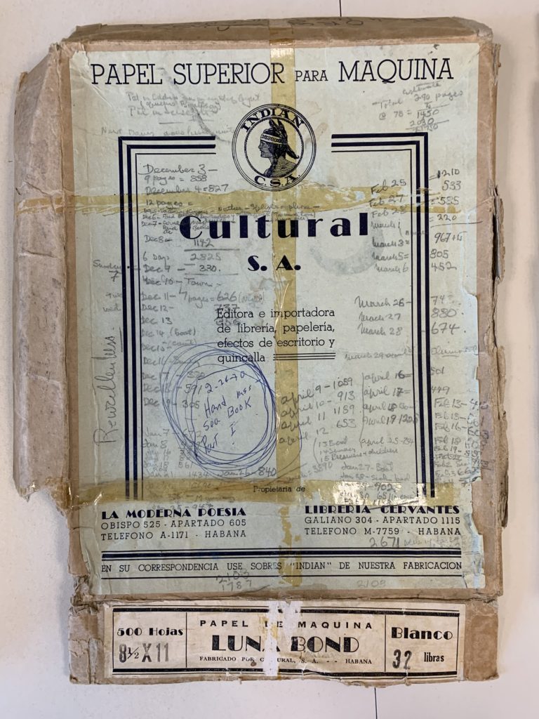 An image of a typewriter paper box lid, extensively damaged torn, flattened, and wrapped in deteriorating tape, with a typed label that reads PAPEL SUPERIOR PARA MAQUINA / CULTURAL S.A." Hemingway's extensive handwritten notations in pencil indicate dates ranging from December to the following April of an undated year, alongside daily word counts.